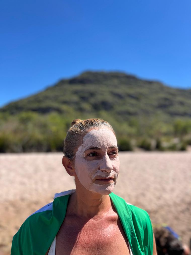 Participante com argila no rosto em frente a um morro da Chapada
