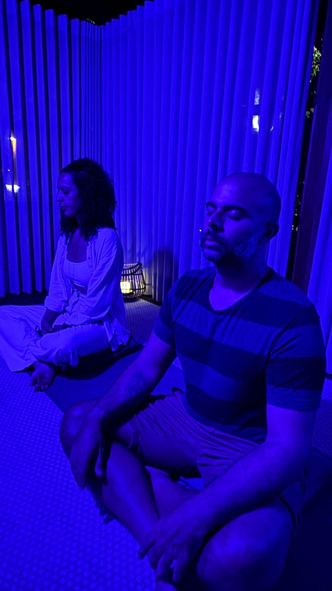 Duas pessoas meditando sob luz azul na tenda terapêutica